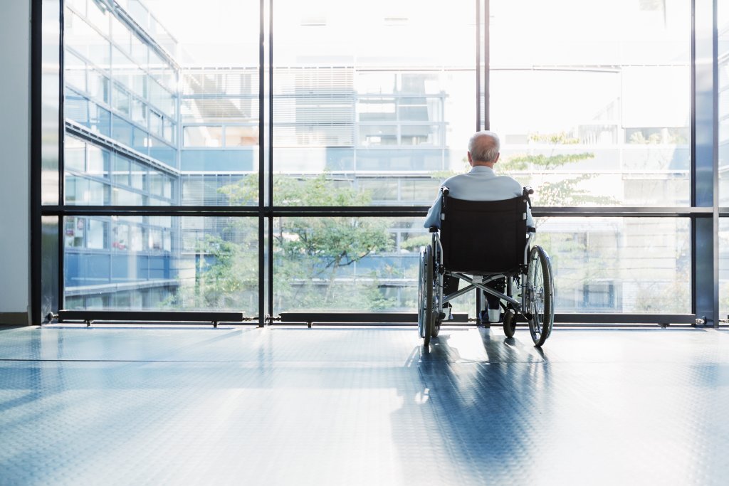 man in rolstoel voor raam